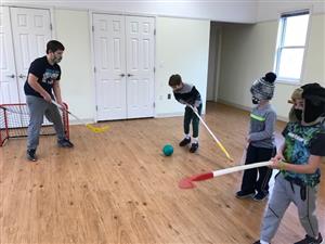 Playing indoor floor hockey during school vacation program.